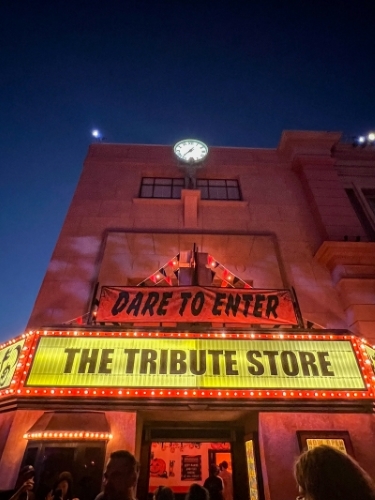 From below, looking up at a building with signs that read "Dare to Enter" and "The Tribute Store" at Halloween Horror Nights. 