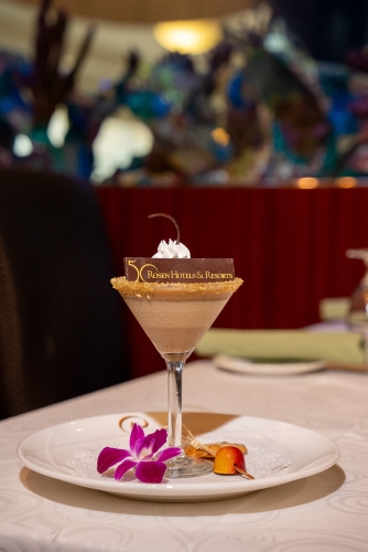 A decadent dessert served in a martini glass topped with a chocolate sign that says "Rosen Hotels & Resorts". 