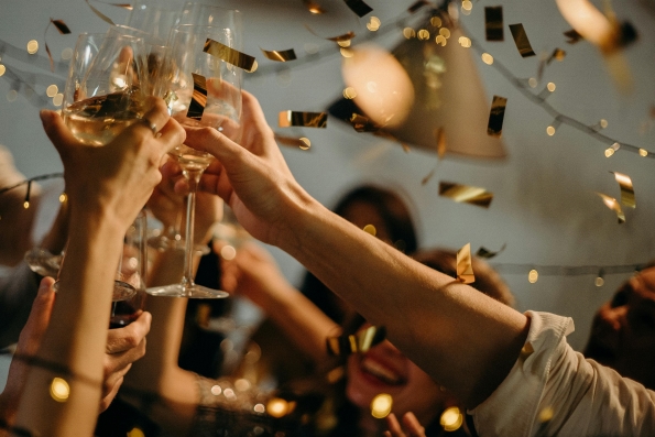 several hands toast glasses of Champagne amidst falling gold confetti. Celebrate New Years Eve in Orlando this year. 