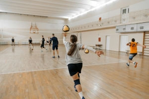 Teens playing volleyball indoors on a court, fitting for the junior volleyball tournament at the Orange County Convention Center.